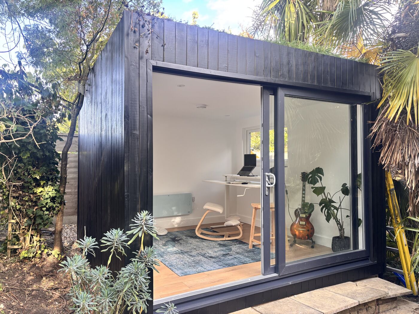 Black-clad garden room with sliding doors, framed by palms