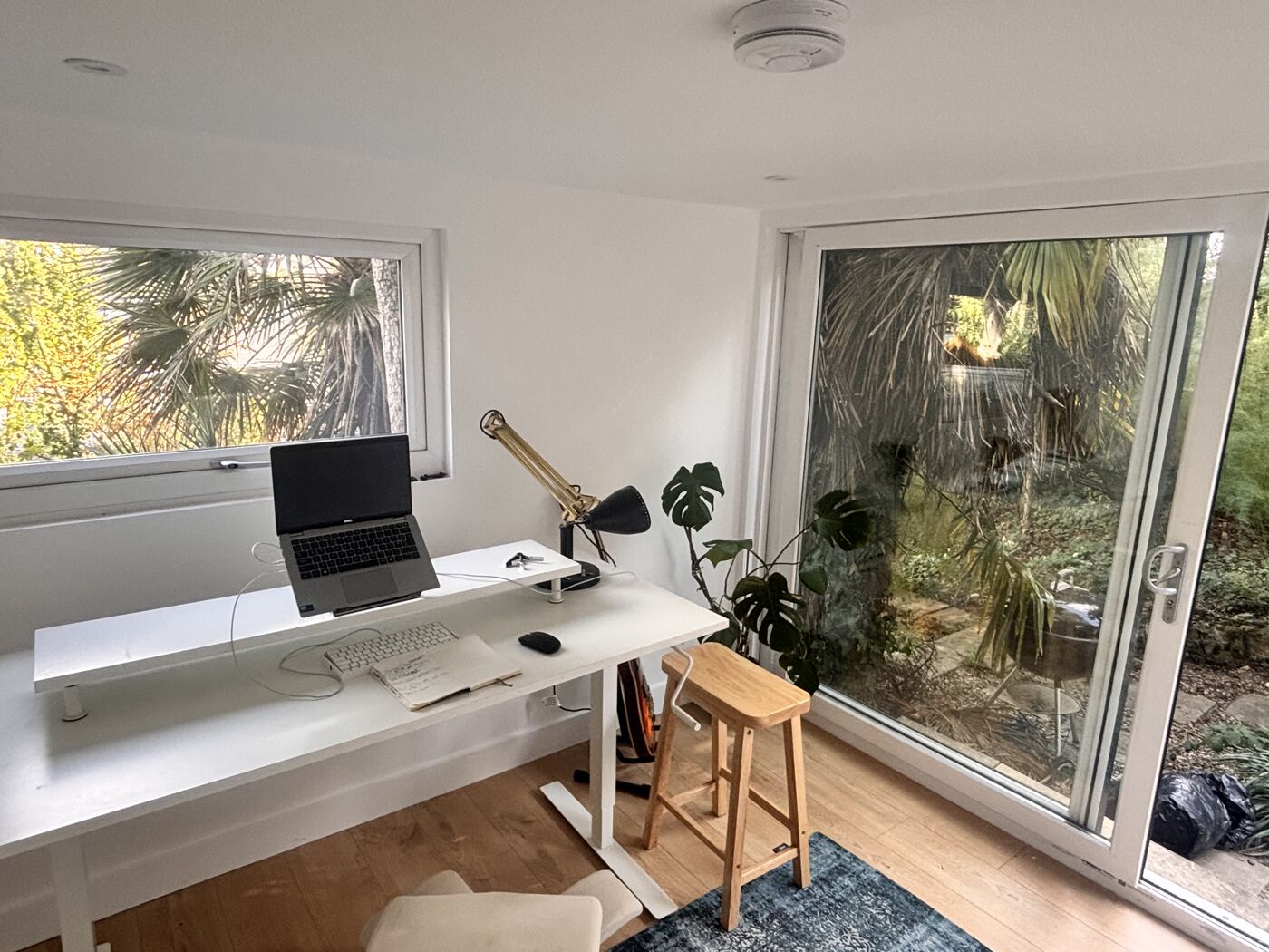 Bright garden office interior with a white desk and sliding doors onto the garden