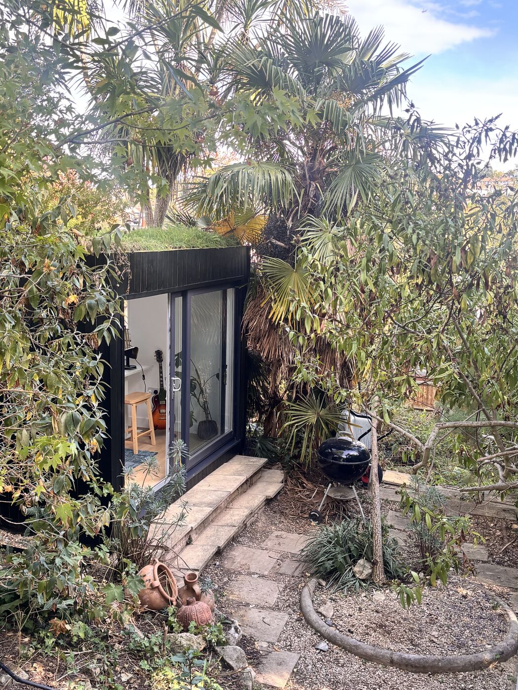 Black-clad garden room tucked among palms and mature planting